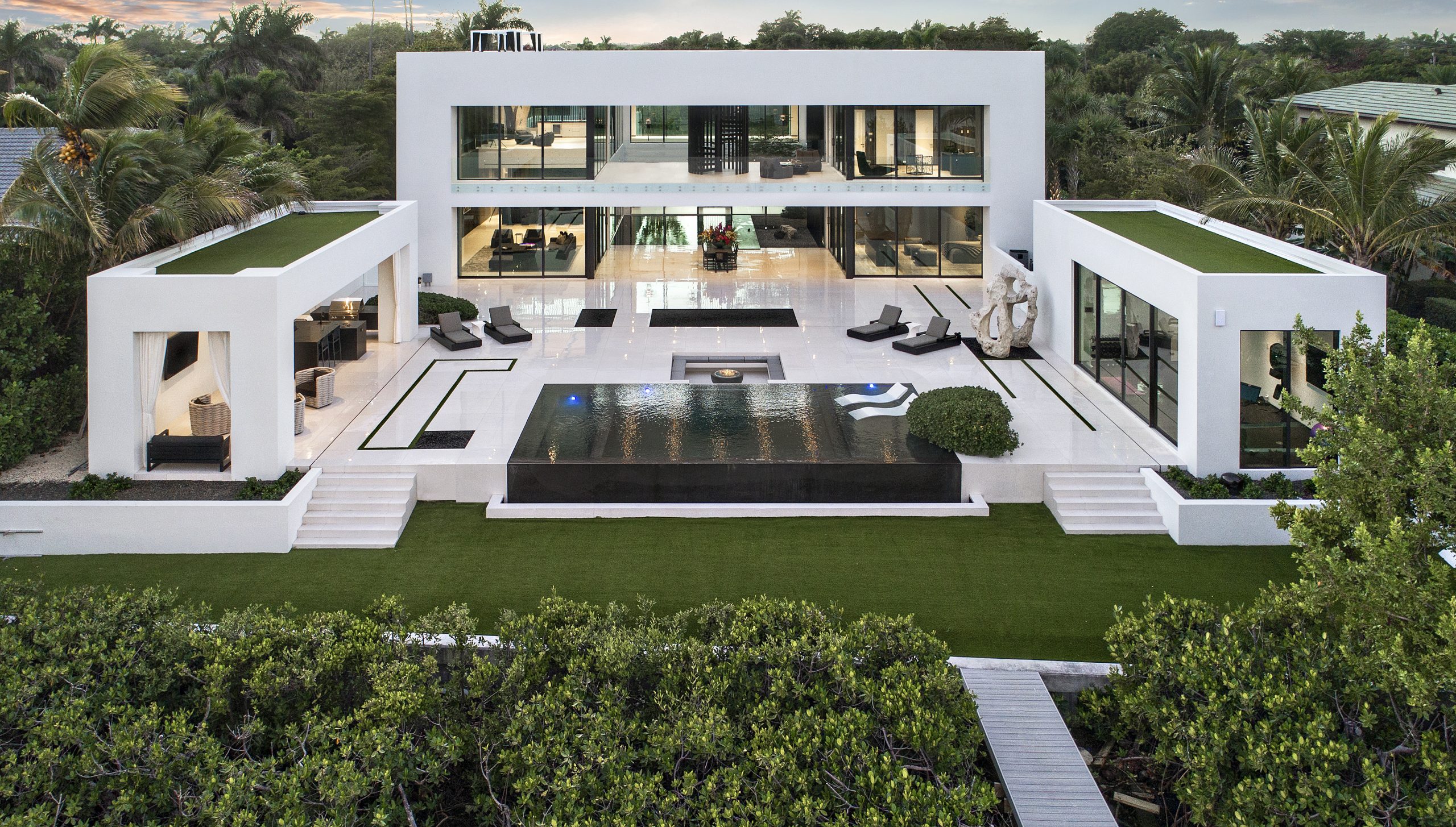 A symmetrical, courtyard-driven residence centered around a strong architectural axis and expansive outdoor living space. Defined by clean volumes, reflective surfaces, and a restrained palette, the home is executed with precision to create a balanced and immersive living environment.
